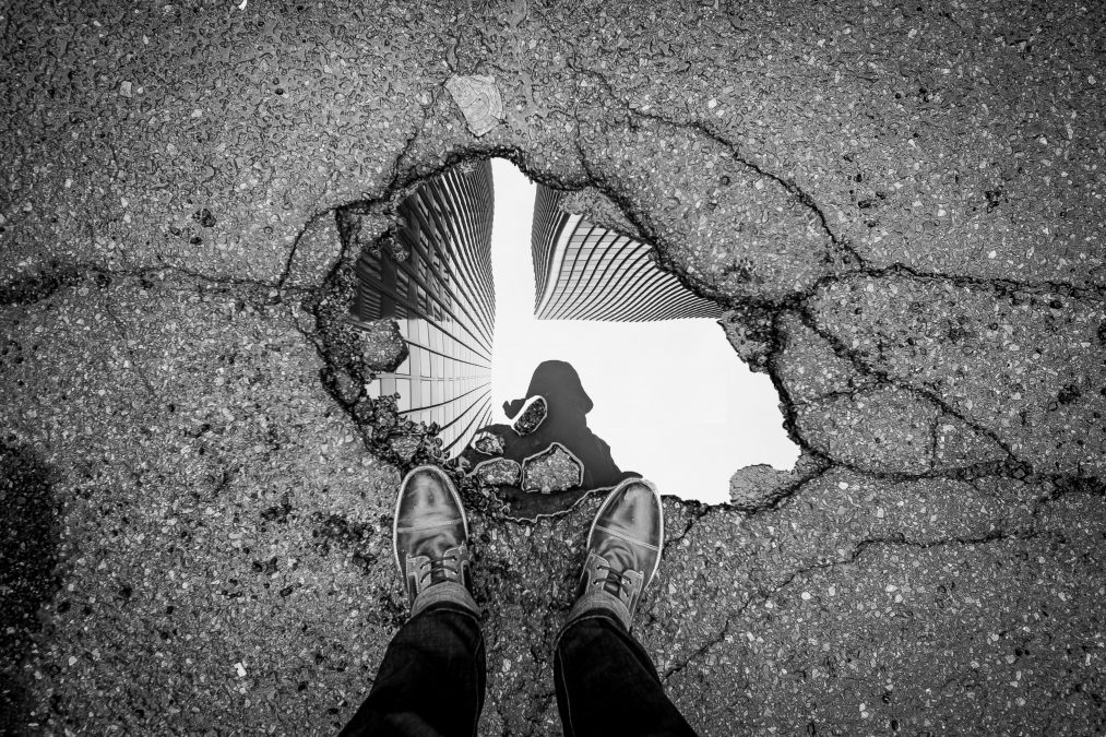 Man looking at his reflection in a puddle.