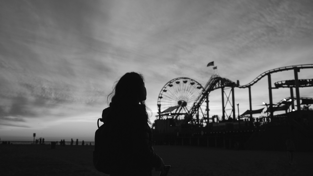 Girl looking at amusement park rollercoaster in the distance